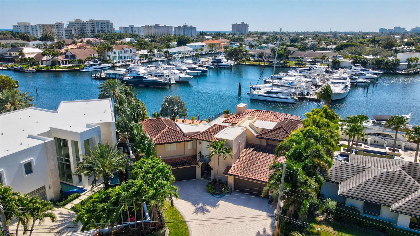 An aerial view shows a waterfront house with a tiled roof and a boat-filled canal — 2850 NE 44th Street, Lighthouse Point FL 33064, LIGHTHOUSE POINT, FL