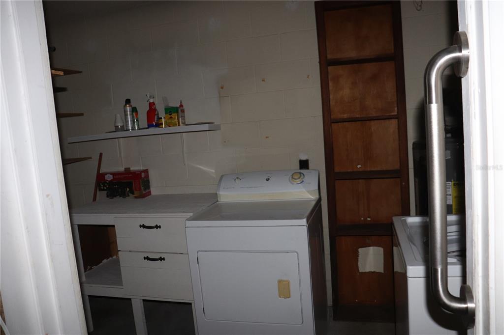 A laundry room features a white dryer, a cabinet, shelving, and a tall wooden unit — 1855 NE 23 STREET, OCALA, FL