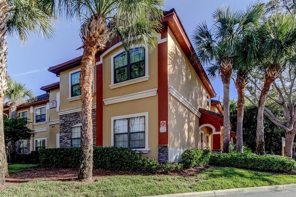 A two-story apartment building with tan stucco walls, red trim, and stone accents — 2279 PORTOFINO PLACE UNIT -2015, PALM HARBOR, FL