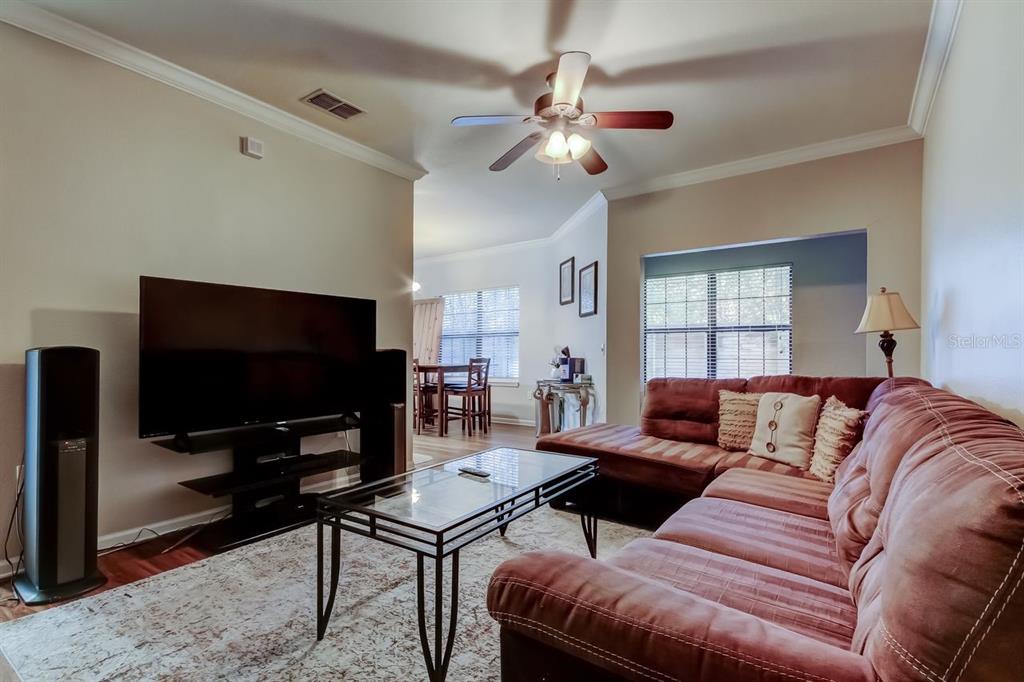 A living room features a brown sectional sofa, a glass coffee table, and a television — 2279 PORTOFINO PLACE UNIT -2015, PALM HARBOR, FL