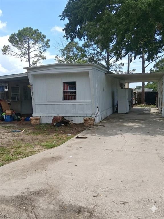 A white mobile home with a concrete driveway and an attached carport under a blue sky — 36449 WEST DRIVE, FRUITLAND PARK, FL