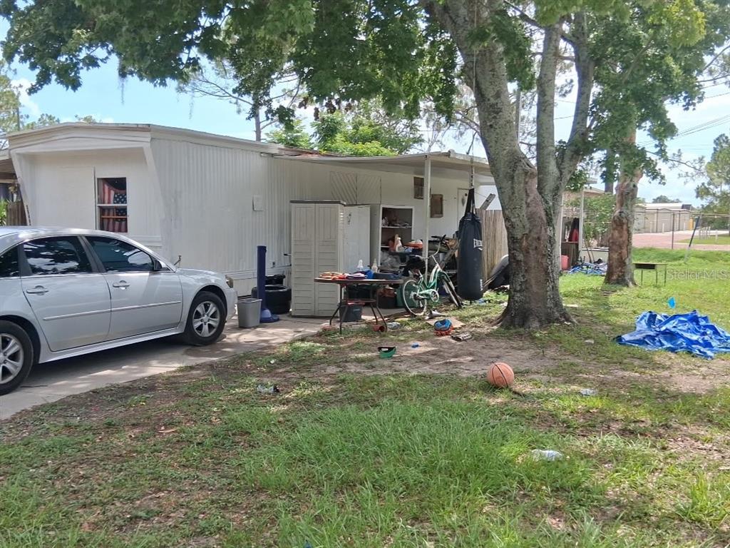 A silver sedan is parked next to a mobile home with a cluttered outdoor area — 36449 WEST DRIVE, FRUITLAND PARK, FL