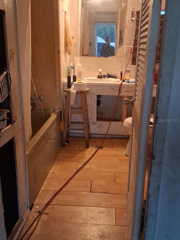 A bathroom under renovation features a bathtub, a vanity without cabinet doors, and wood-look flooring — 36449 WEST DRIVE, FRUITLAND PARK, FL