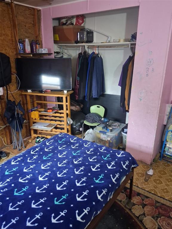 A bedroom features a bed with an anchor-patterned blanket, a television stand, and an open closet — 36449 WEST DRIVE, FRUITLAND PARK, FL