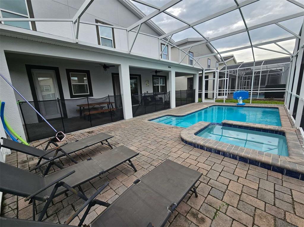 A screened-in patio features a swimming pool, a hot tub, and several lounge chairs — 1241 CHALLENGE DRIVE, DAVENPORT, FL