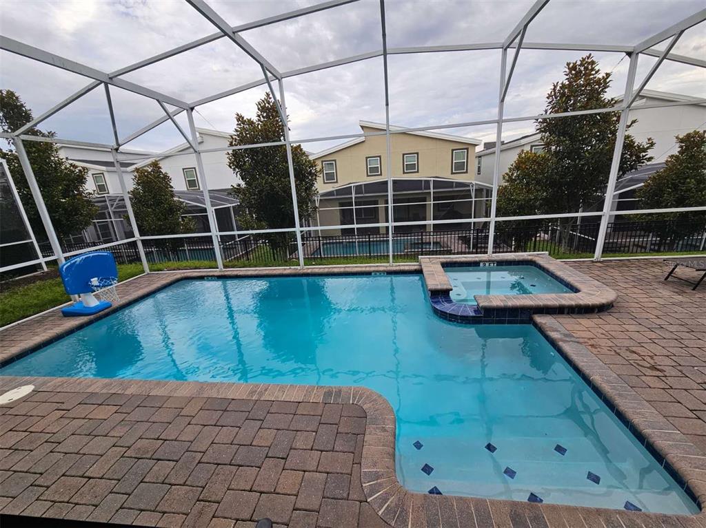 A swimming pool and spa are enclosed within a screened lanai with brick pavers — 1241 CHALLENGE DRIVE, DAVENPORT, FL