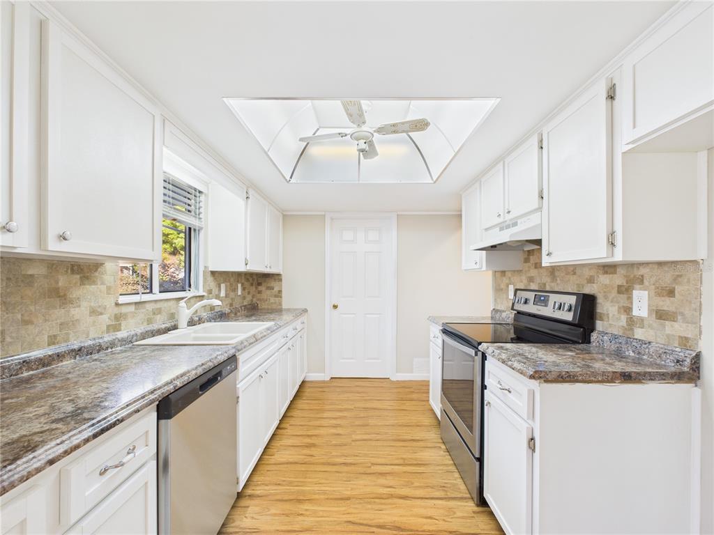 A kitchen with white cabinets, granite-look countertops, stainless steel appliances, and a recessed ceiling fan — 8430 SW 105TH PLACE, OCALA, FL