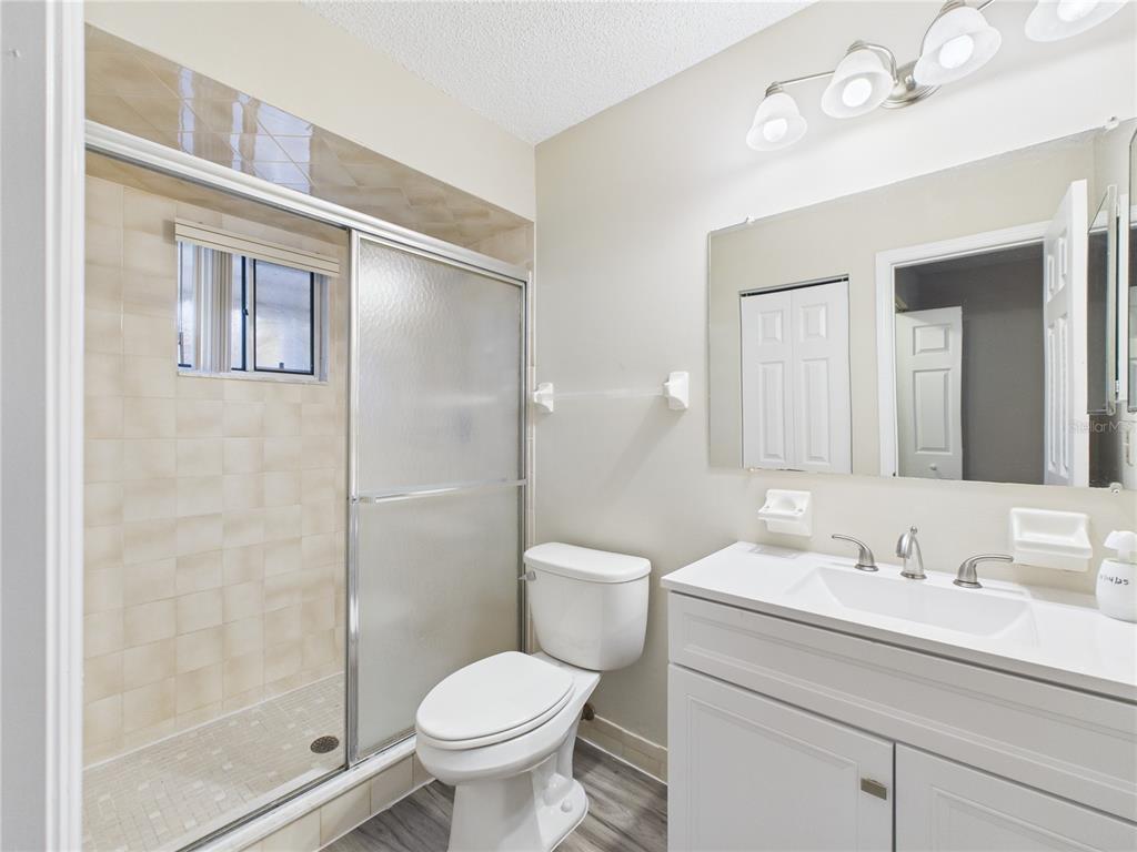 A bathroom features a walk-in shower with sliding glass doors, a toilet, and a vanity — 8430 SW 105TH PLACE, OCALA, FL