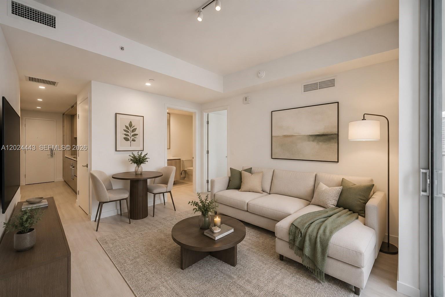 A modern living room features a beige sectional sofa, a round coffee table, and a dining area — 77 SE 5th st # 2305, Miami FL 33131, MIAMI, FL