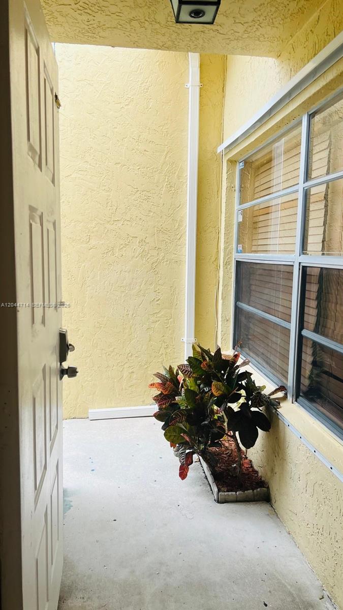 A view from an open doorway looking out onto a small, yellow-walled exterior patio — 7394 NW 34th St, Lauderhill FL 33319, LAUDERHILL, FL