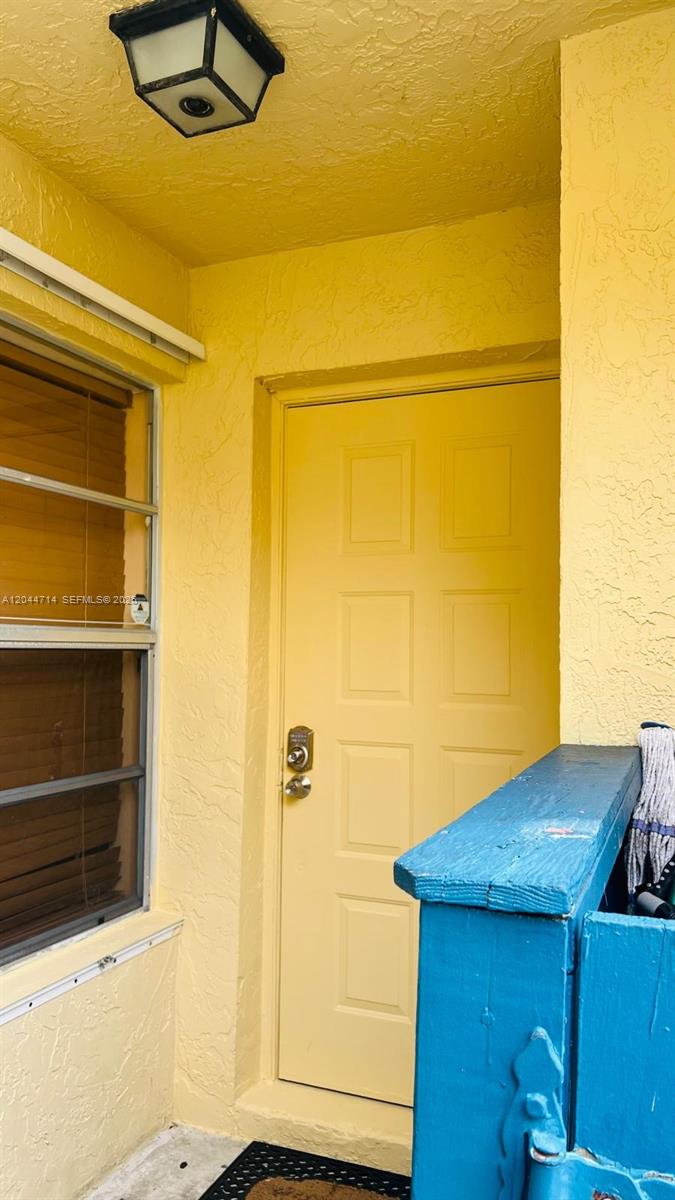 A yellow exterior door with a window to the left and a blue structure nearby — 7394 NW 34th St, Lauderhill FL 33319, LAUDERHILL, FL