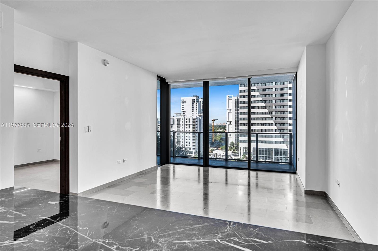 An empty room features light-colored tile flooring, white walls, and floor-to-ceiling windows overlooking city buildings — 88 SW 7th St # 806, Miami FL 33130, MIAMI, FL