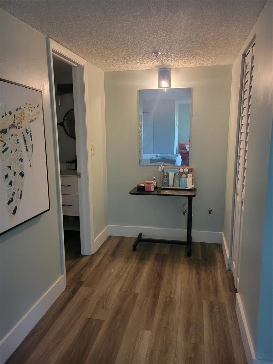 A hallway features light blue walls, wood-look flooring, a mirror, and a small rolling desk — 3940 Inverrary Boulevard # a, Lauderhill FL 33319, LAUDERHILL, FL