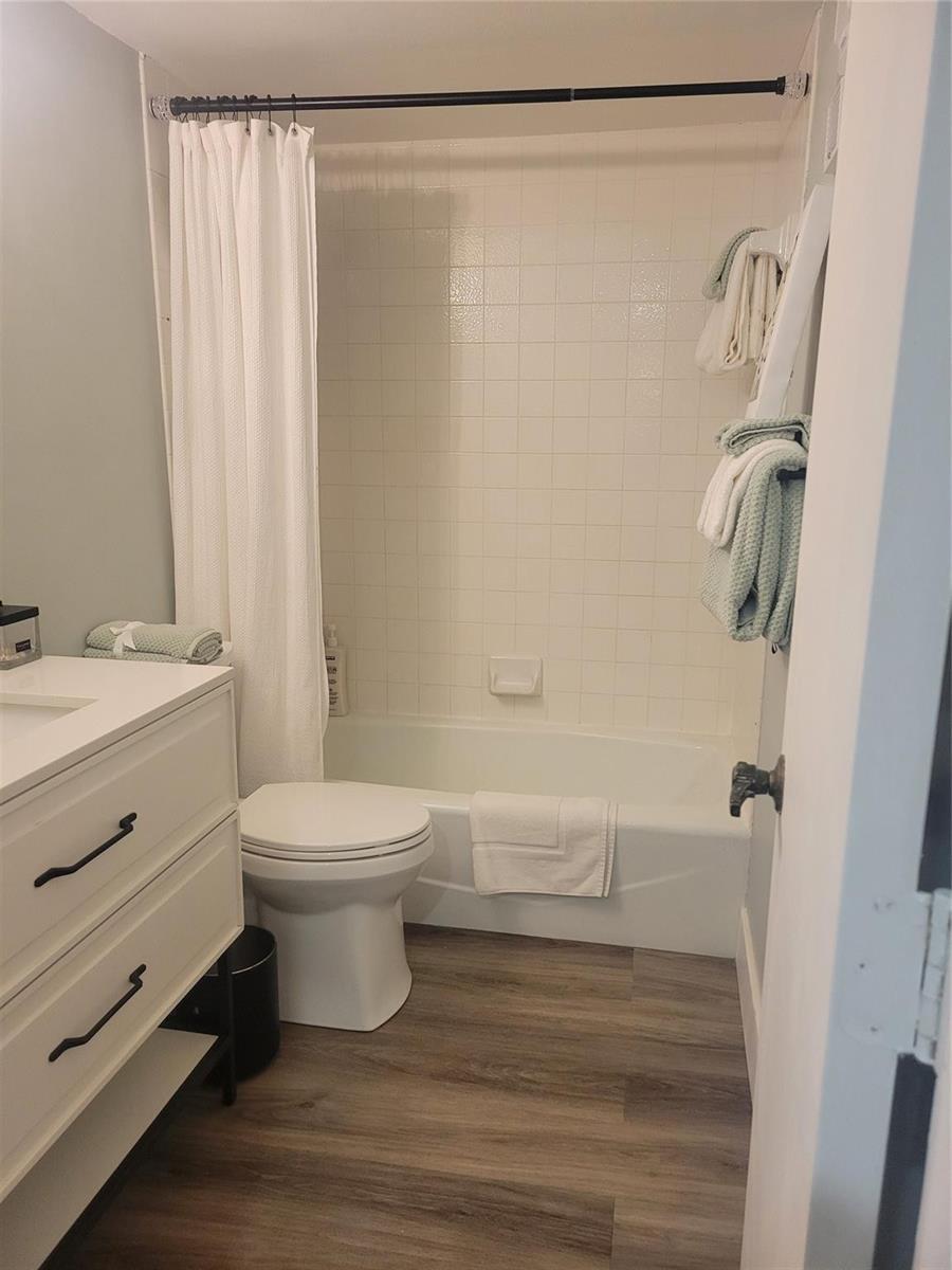 A bathroom features a white vanity, a toilet, and a shower-tub combo with white tile — 3940 Inverrary Boulevard # a, Lauderhill FL 33319, LAUDERHILL, FL
