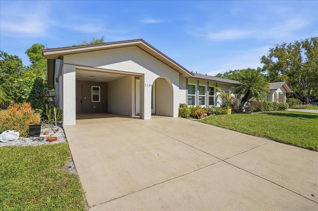 A single-story house features a concrete driveway, a covered carport, and a grassy front yard — 3759 COLLINS STREET UNIT 711, SARASOTA, FL