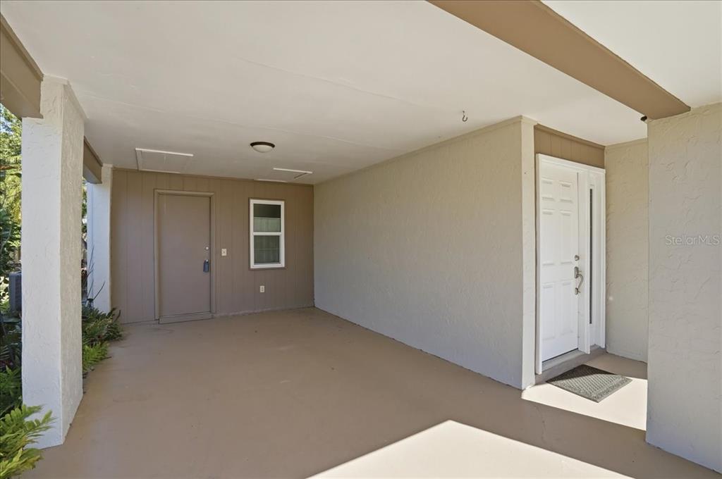 A covered entryway features a concrete floor, a white front door, and a side door — 3759 COLLINS STREET UNIT 711, SARASOTA, FL