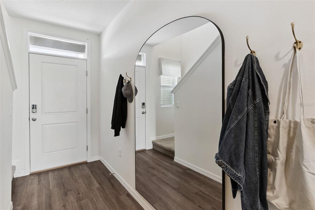 A bright entryway features wood-look flooring, a large arched floor mirror, and wall-mounted coat hooks — 4290 BUTTERSCOTCH CIRCLE, LAKELAND, FL