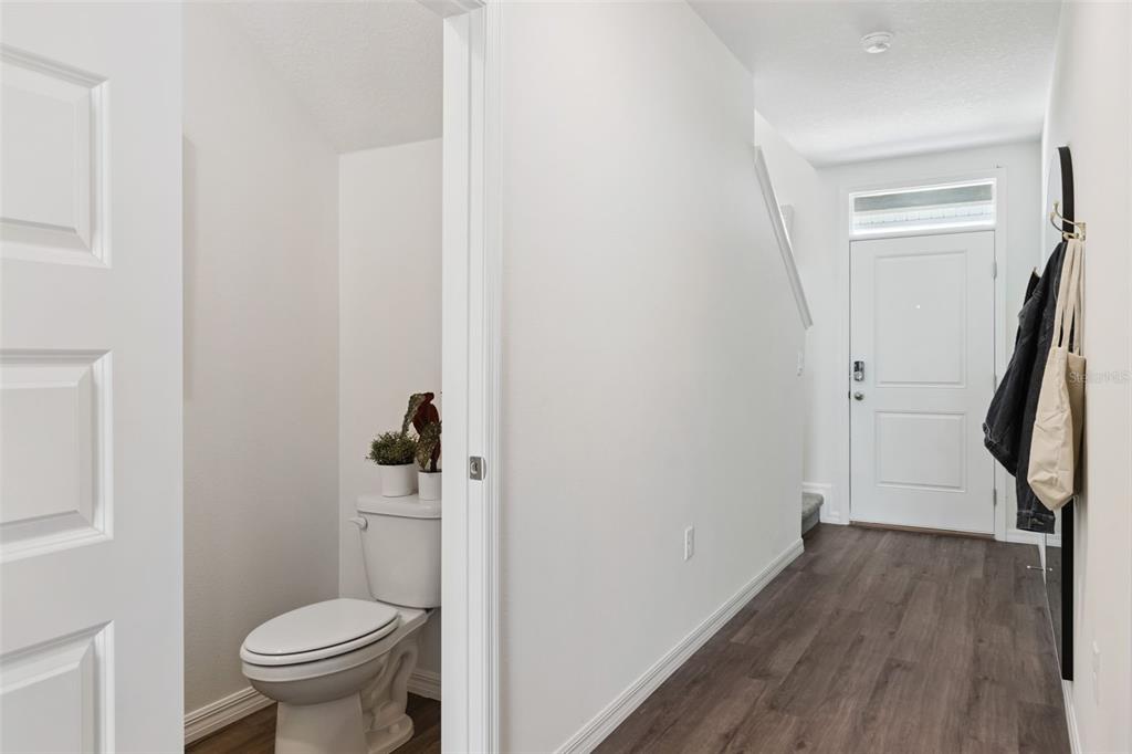 A small bathroom with a toilet sits next to a hallway leading to an entry door — 4290 BUTTERSCOTCH CIRCLE, LAKELAND, FL
