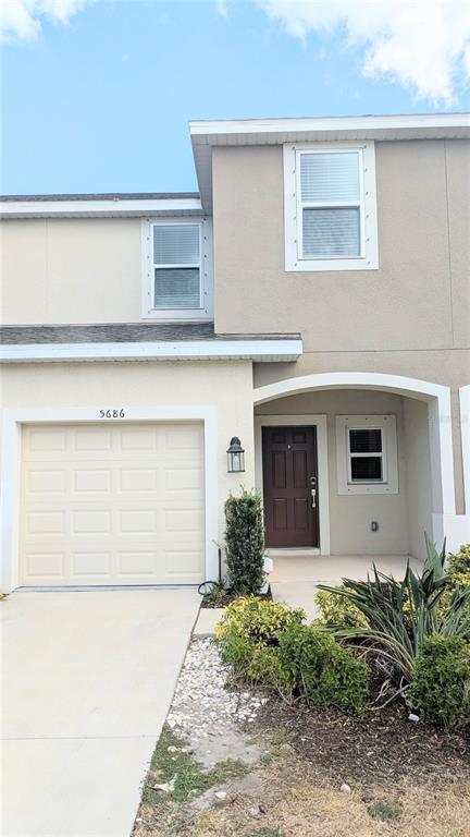 A two-story townhouse exterior features a beige stucco facade, a single-car garage, and a covered entryway — 5686 ARCHIPELAGO STREET, NOKOMIS, FL