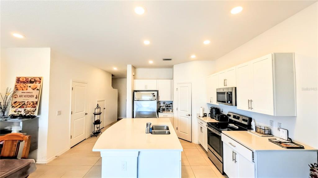 A bright kitchen features white cabinets, a central island with a sink, and stainless appliances — 5686 ARCHIPELAGO STREET, NOKOMIS, FL