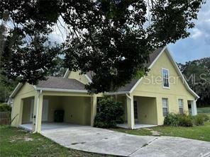 A yellow two-story house features a covered carport and a concrete driveway — 130 N BOSTON AVENUE, DELAND, FL