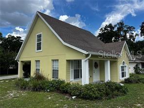 A yellow, two-story house with a brown shingled roof and a covered front porch — 130 N BOSTON AVENUE, DELAND, FL