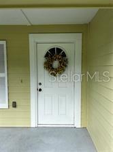 A white front door with a decorative wreath is set in a light yellow wall — 130 N BOSTON AVENUE, DELAND, FL