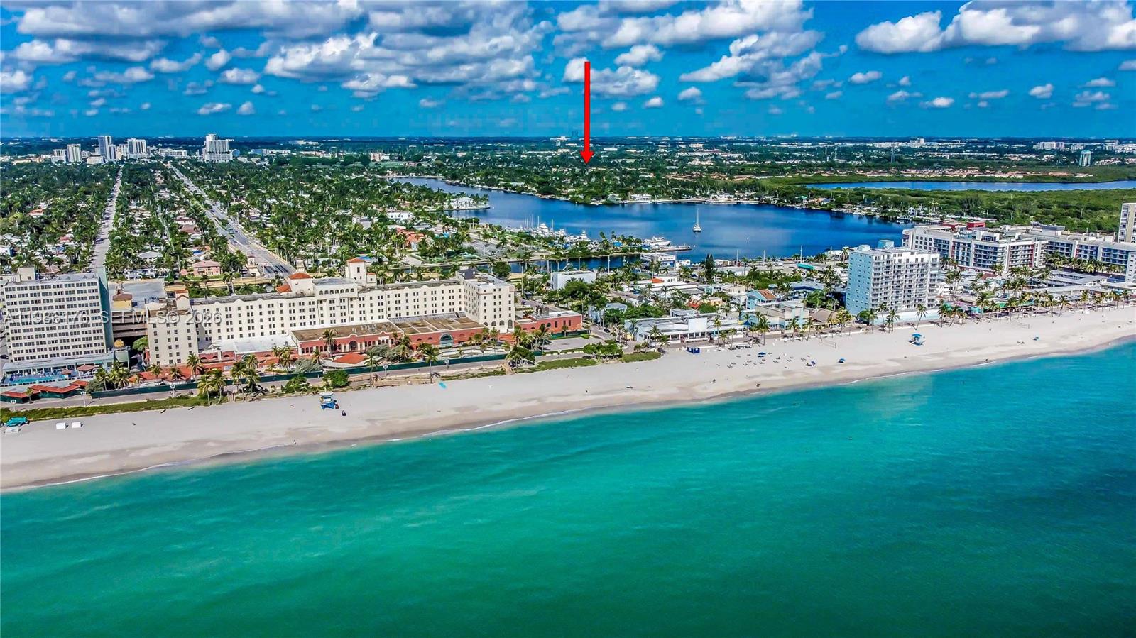 An aerial view shows a sandy beach, turquoise ocean, and a coastal city with buildings — 1523 Johnson St, Hollywood FL 33020, HOLLYWOOD, FL