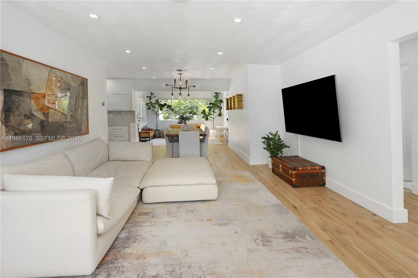 A living room features a white sectional sofa, a wall-mounted television, and a dining area — 1523 Johnson St, Hollywood FL 33020, HOLLYWOOD, FL