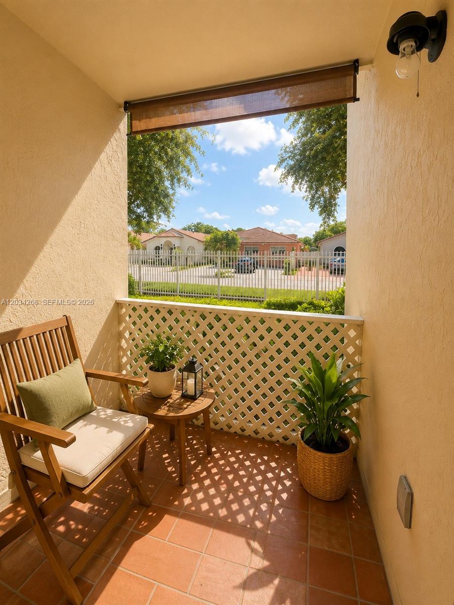 A small balcony features a wooden chair, a side table with a plant, and lattice railing — 3041 W 76th St # 108, Hialeah FL 33018, HIALEAH, FL