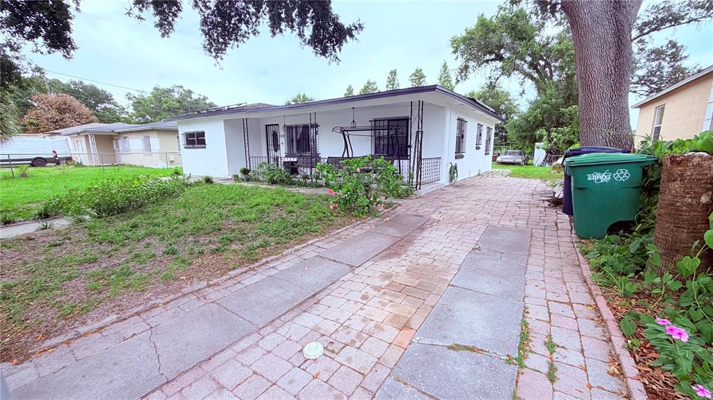 A white single-story house with a paved driveway and a green trash bin outside — 1709 E NORTH BAY STREET, TAMPA, FL