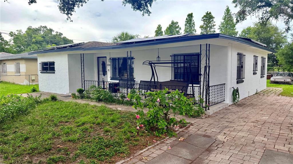 A white single-story house features a covered front porch with a swing and solar panels — 1709 E NORTH BAY STREET, TAMPA, FL