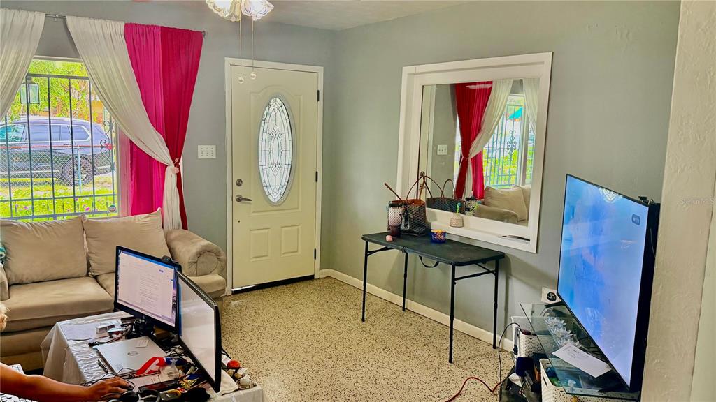 A living room features a beige sofa, a computer desk, a television, and a front door — 1709 E NORTH BAY STREET, TAMPA, FL