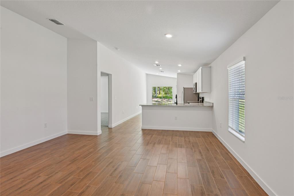 An open-concept living area features wood-look tile flooring, white walls, and a kitchen island — 14034 RICEBIRD AVENUE, WEEKI WACHEE, FL
