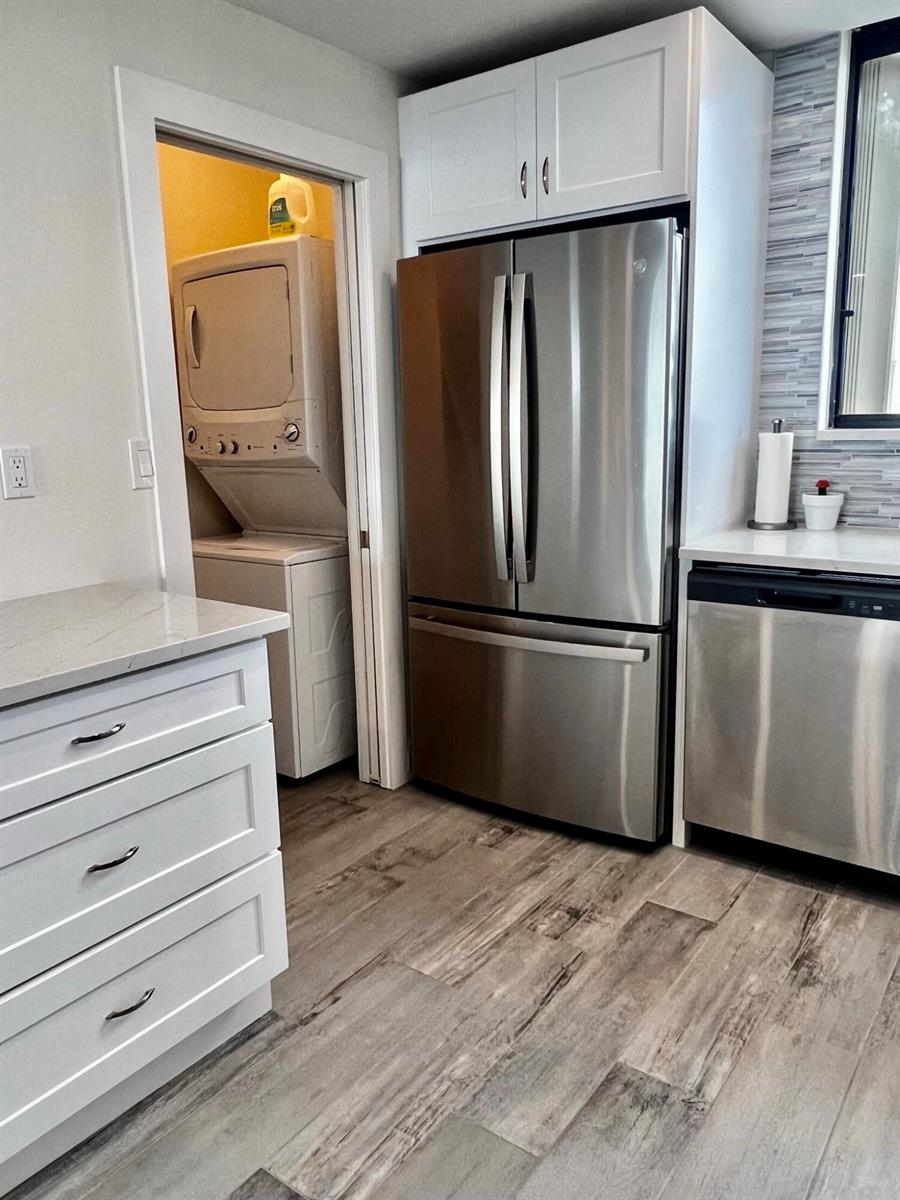 A kitchen features white cabinets, stainless steel appliances, and a doorway leading to a laundry area — 300 Ocean Trail Way # 510, Jupiter FL 33477, JUPITER, FL