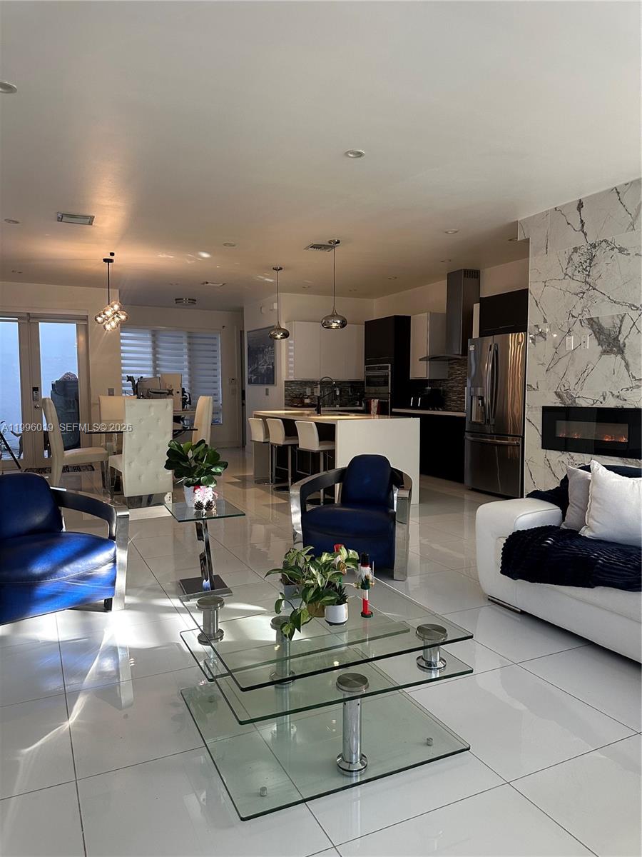 An open-concept living area features white tile floors, a marble fireplace, and a modern kitchen — 10361 NW 64th Ter, Doral FL 33178, DORAL, FL