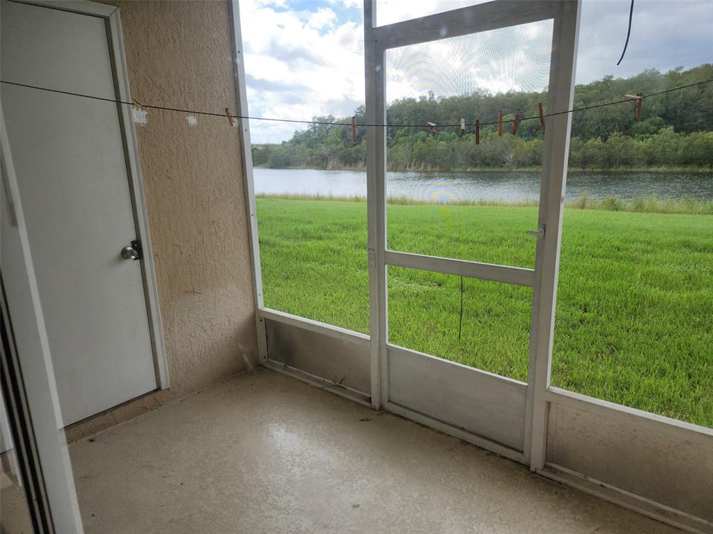 A screened-in porch with a concrete floor overlooks a grassy lawn and a lake — 13336 FAIRWAY GLEN DRIVE UNIT 104, ORLANDO, FL