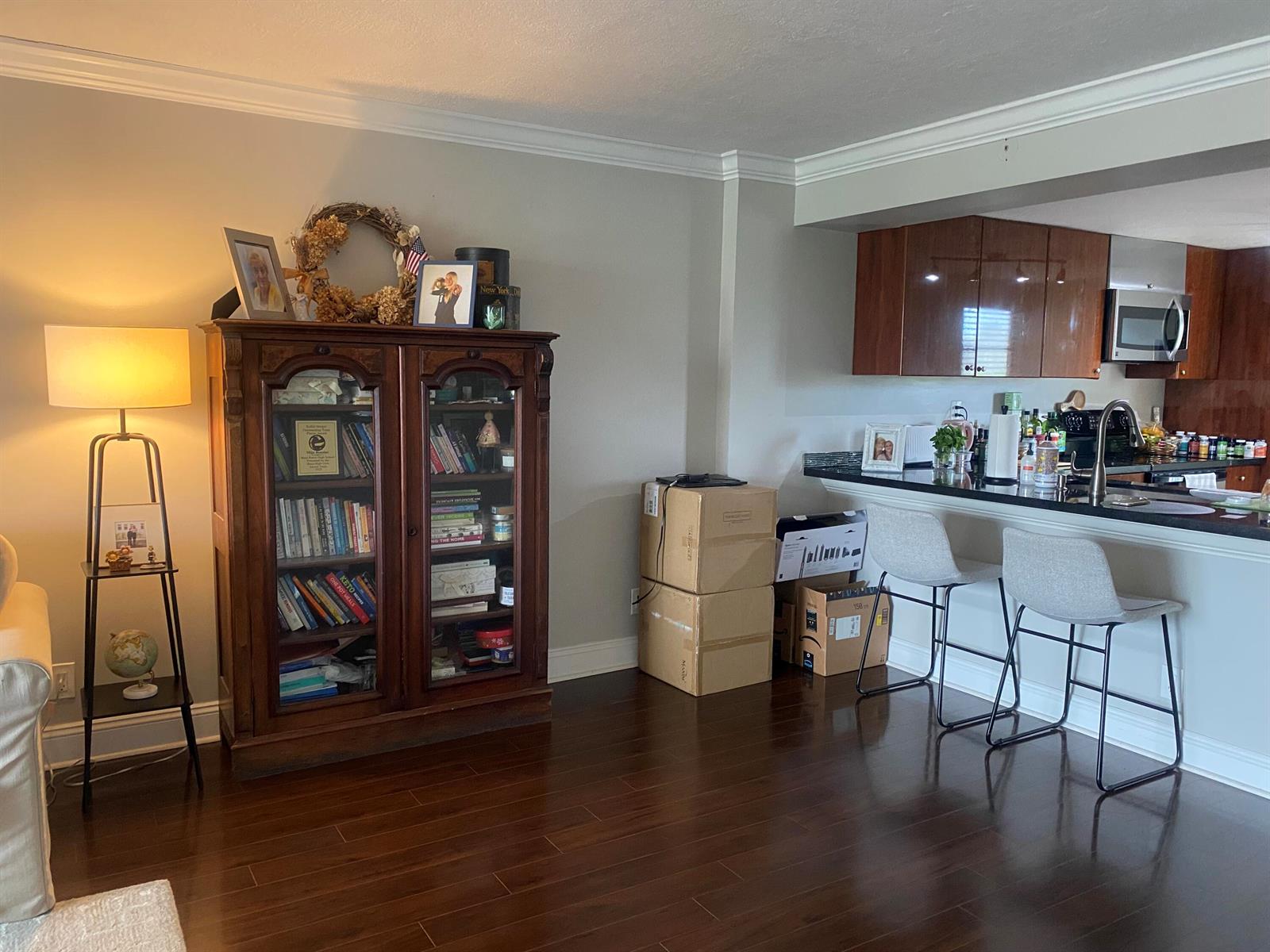 A living room with a wooden bookshelf, floor lamp, and a kitchen counter with bar stools — 9 Royal Palm Way # 403, Boca Raton FL 33432, BOCA RATON, FL