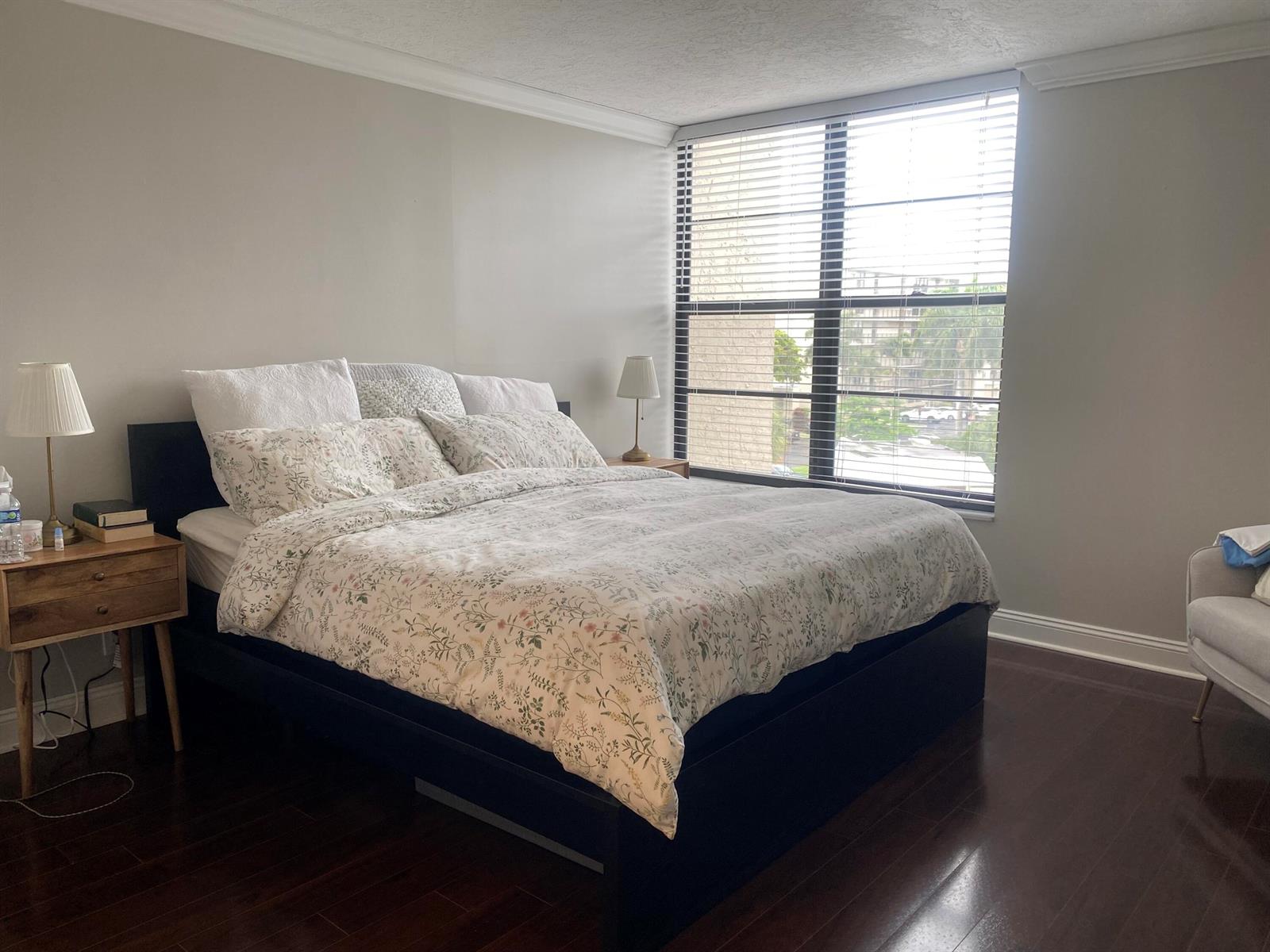 A bedroom features a dark bed frame, floral bedding, wooden nightstands, and a large window — 9 Royal Palm Way # 403, Boca Raton FL 33432, BOCA RATON, FL
