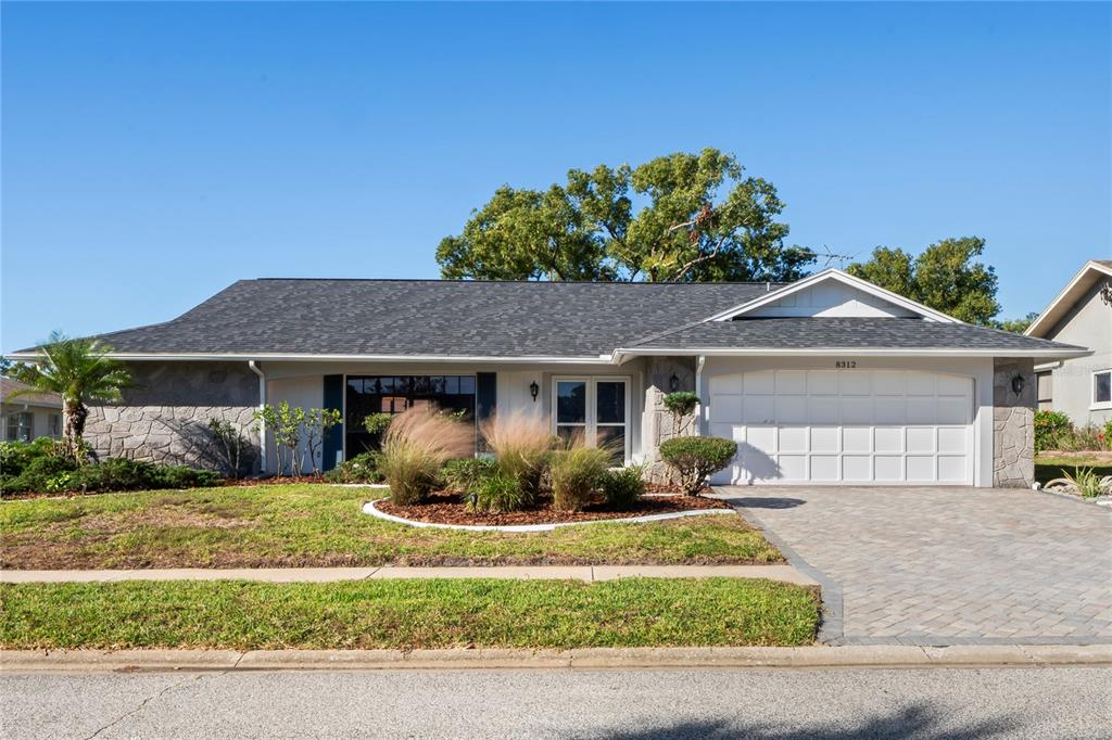 A single-story house with a stone facade, a two-car garage, and a paved driveway — 8312 ROXBORO DRIVE, HUDSON, FL