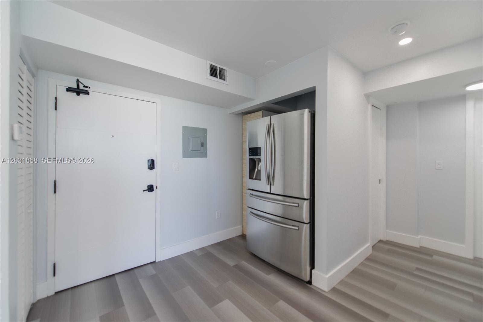 A stainless steel refrigerator is recessed into a wall next to a white entry door — 1800 NW 24th Ave # 712, Miami FL 33125, MIAMI, FL