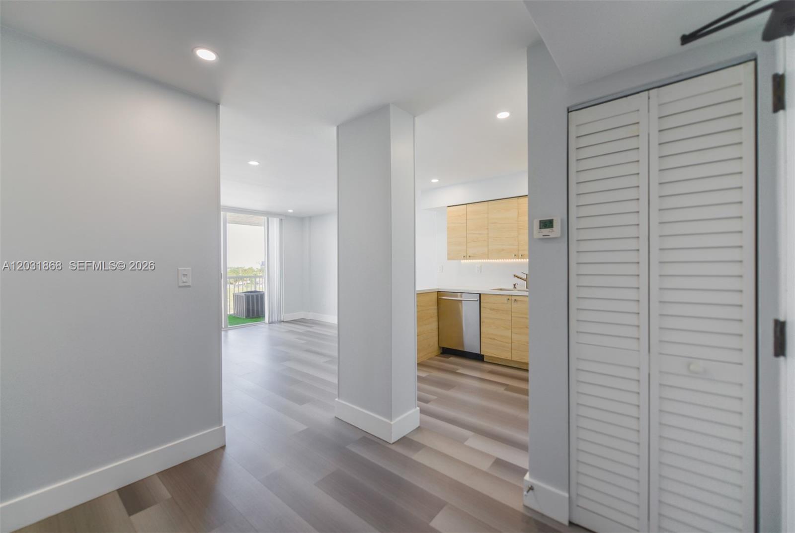 A view from a hallway looking toward a kitchen with light wood cabinets and balcony — 1800 NW 24th Ave # 712, Miami FL 33125, MIAMI, FL