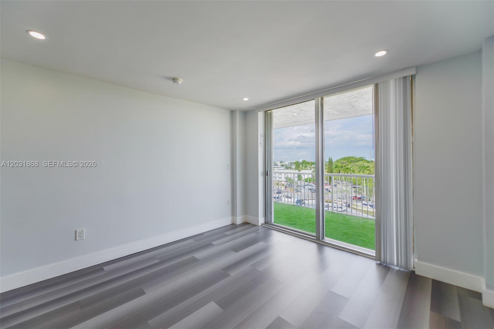 An empty room features gray wood-look flooring, white walls, recessed lighting, and a sliding glass door — 1800 NW 24th Ave # 712, Miami FL 33125, MIAMI, FL