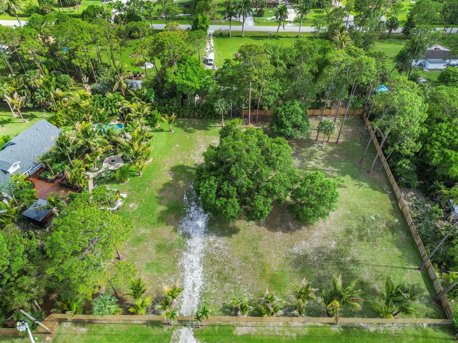An aerial view shows a large, fenced backyard with mature trees and a wooden deck — 13530 42nd Road N, West Palm Beach FL 33411, WEST PALM BEACH, FL