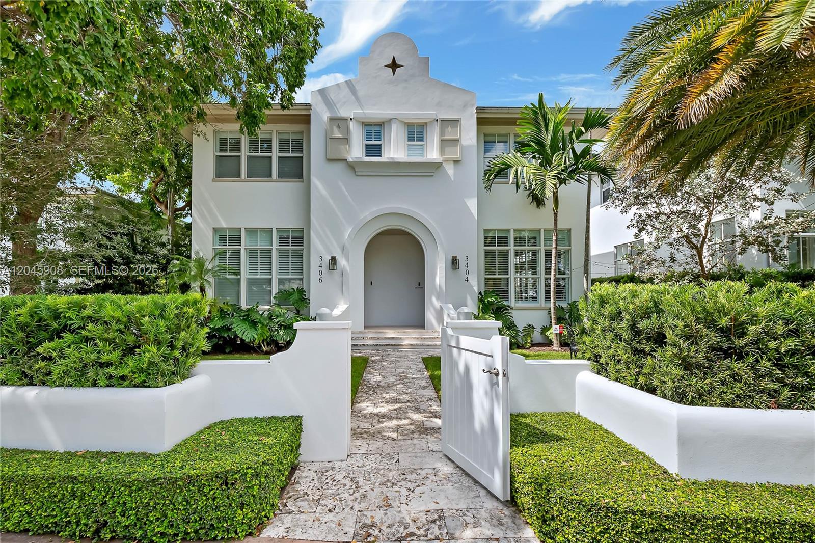 A two-story white stucco house features an arched entryway and a stone walkway — 3406 Ponce De Leon Blvd, Coral Gables FL 33134, CORAL GABLES, FL