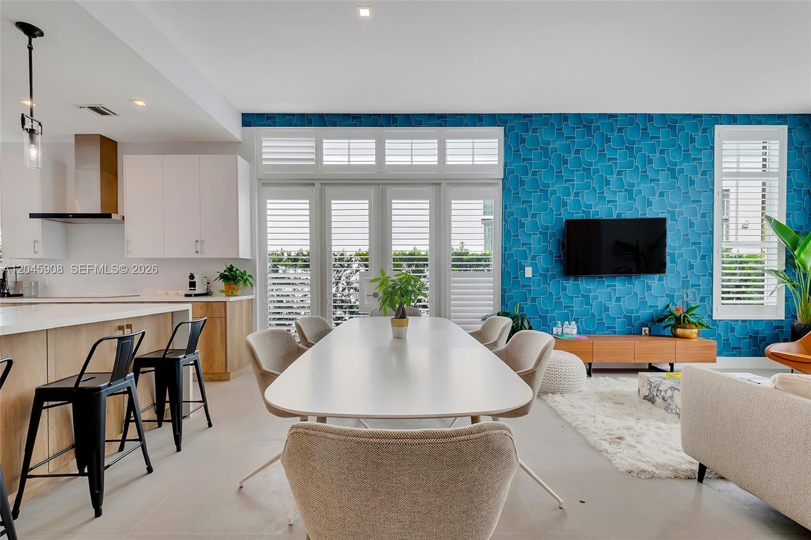A dining area and living room feature a blue patterned accent wall and white shutters — 3406 Ponce De Leon Blvd, Coral Gables FL 33134, CORAL GABLES, FL