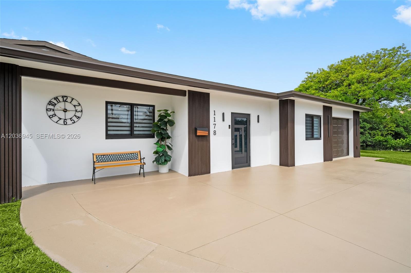 The exterior of a single-story house features a white facade, brown vertical accents, and a driveway — 1178 Grant St, Hollywood FL 33019, HOLLYWOOD, FL