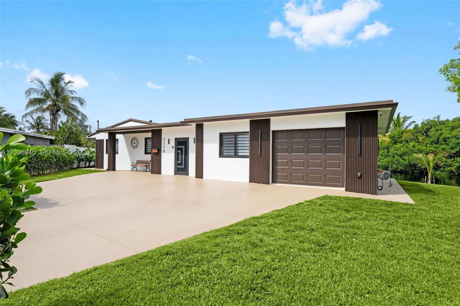 A single-story house with a white facade, dark brown accents, and a concrete driveway — 1178 Grant St, Hollywood FL 33019, HOLLYWOOD, FL