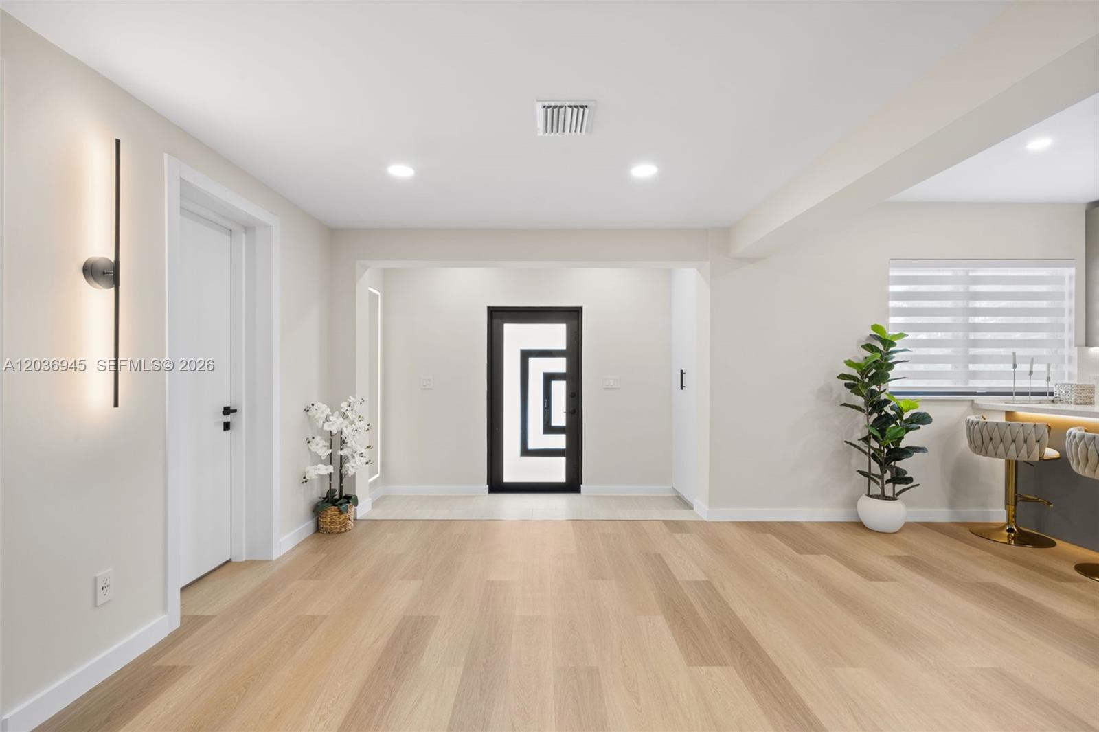 A modern, light-filled entryway features wood-look flooring, a geometric front door, and recessed lighting — 1178 Grant St, Hollywood FL 33019, HOLLYWOOD, FL