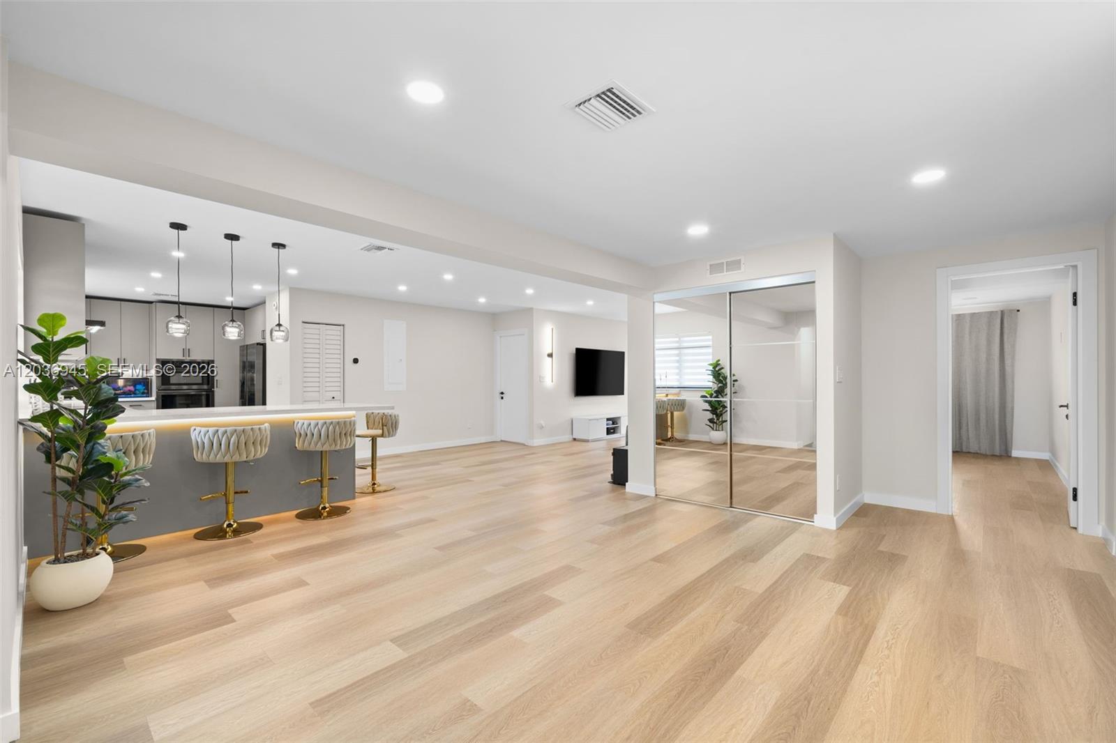 An open-concept living area features light wood flooring, a kitchen island with barstools, and mirrored closets — 1178 Grant St, Hollywood FL 33019, HOLLYWOOD, FL